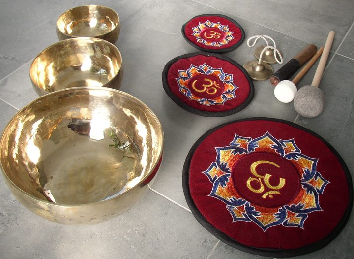 Zusammengestelltes Set aus Klangschalen, Klöppeln und bestickten Kissen