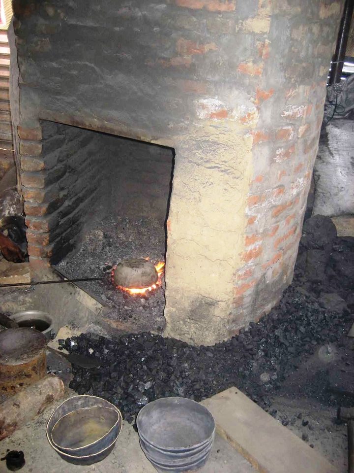 Gemauerter Schmelzofen mit Schalen und Werkzeug davor