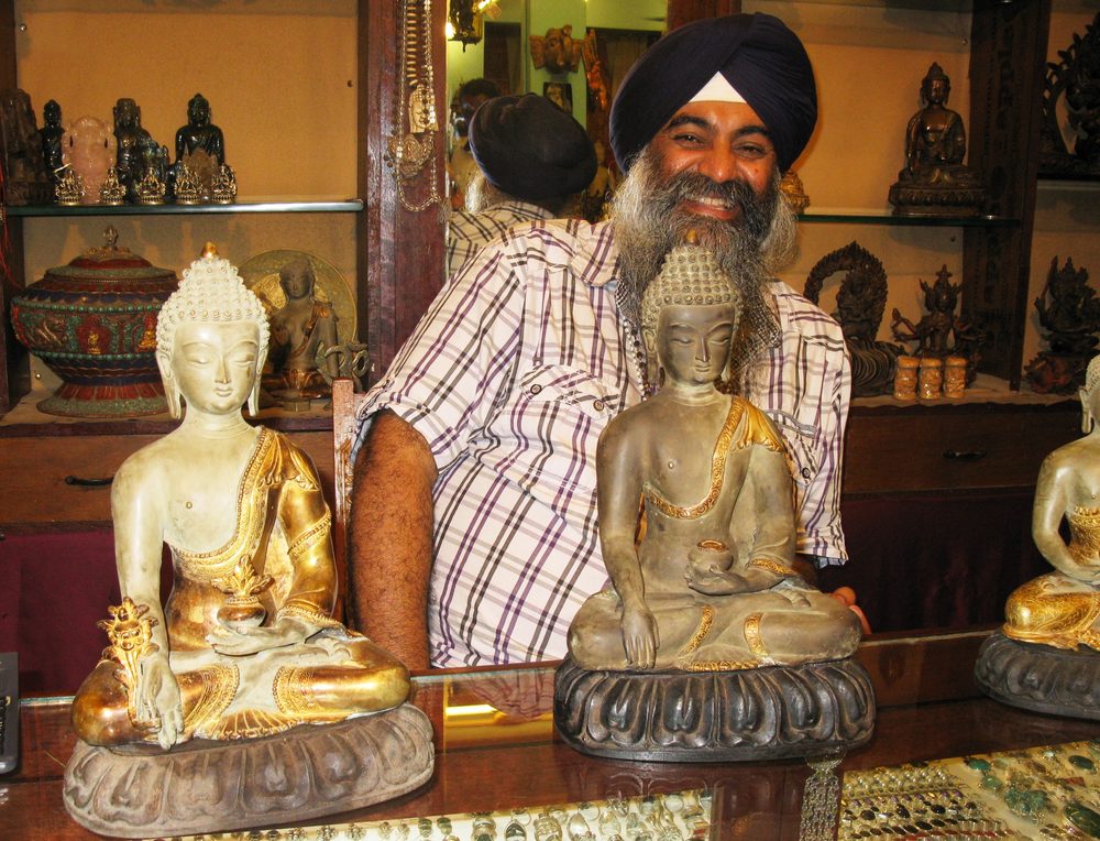 Ladenraum in Indien mit Buddhafiguren, Schalen und Messinggerät