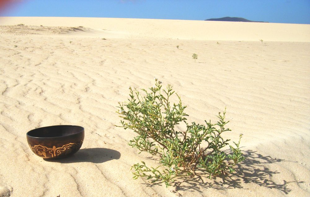 Verzierte tibetische Klangschale im Sand einer Düne
