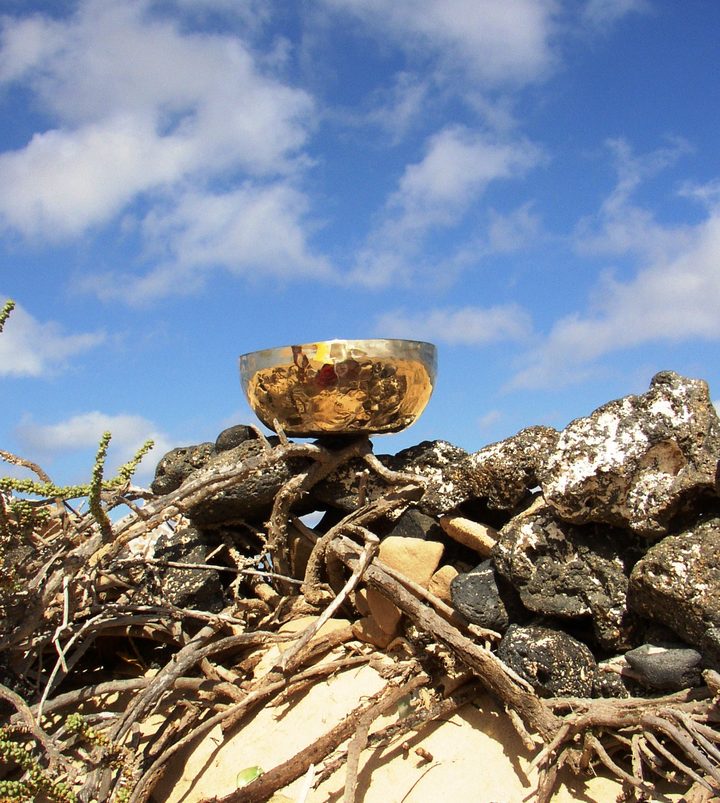 Klangschale auf Treibholz vor blauem Himmel