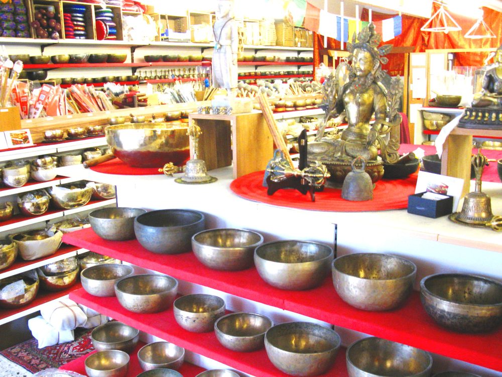 Showroom mit Buddhafigur und gestuften Regalen voller Klangschalen