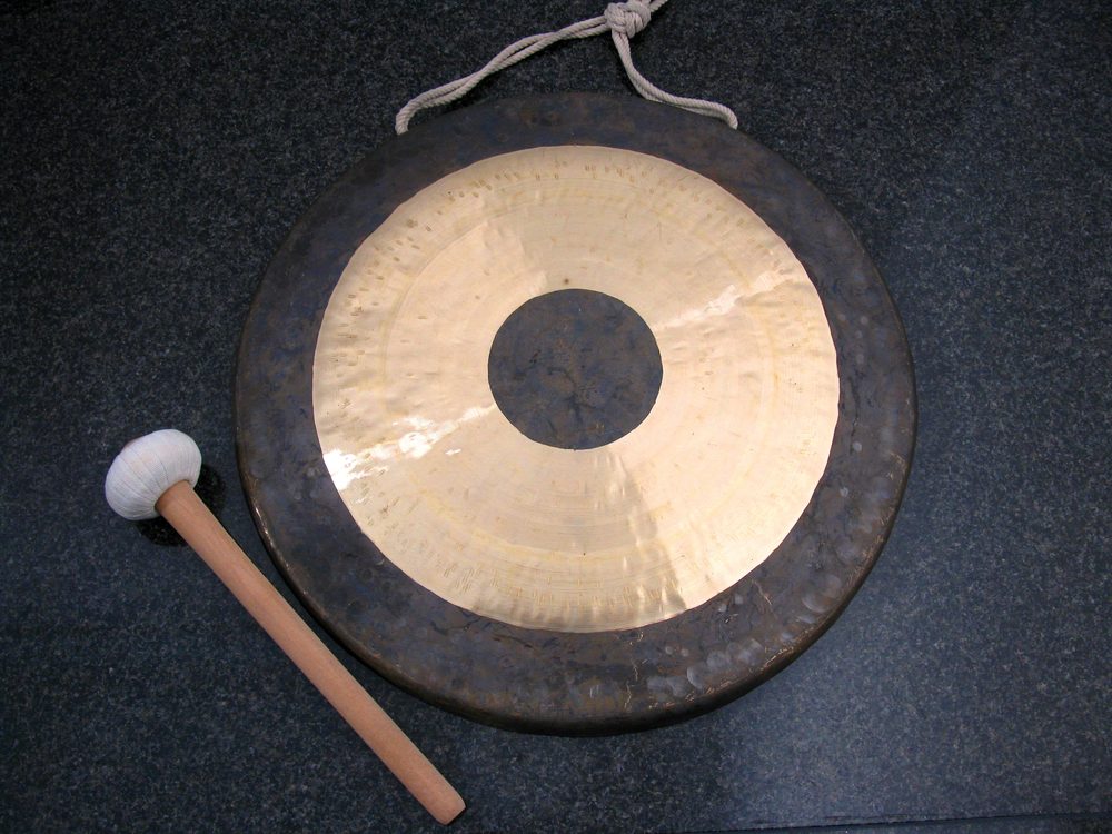 Tamtam-Gong mit Schlägel auf dunklem Untergrund